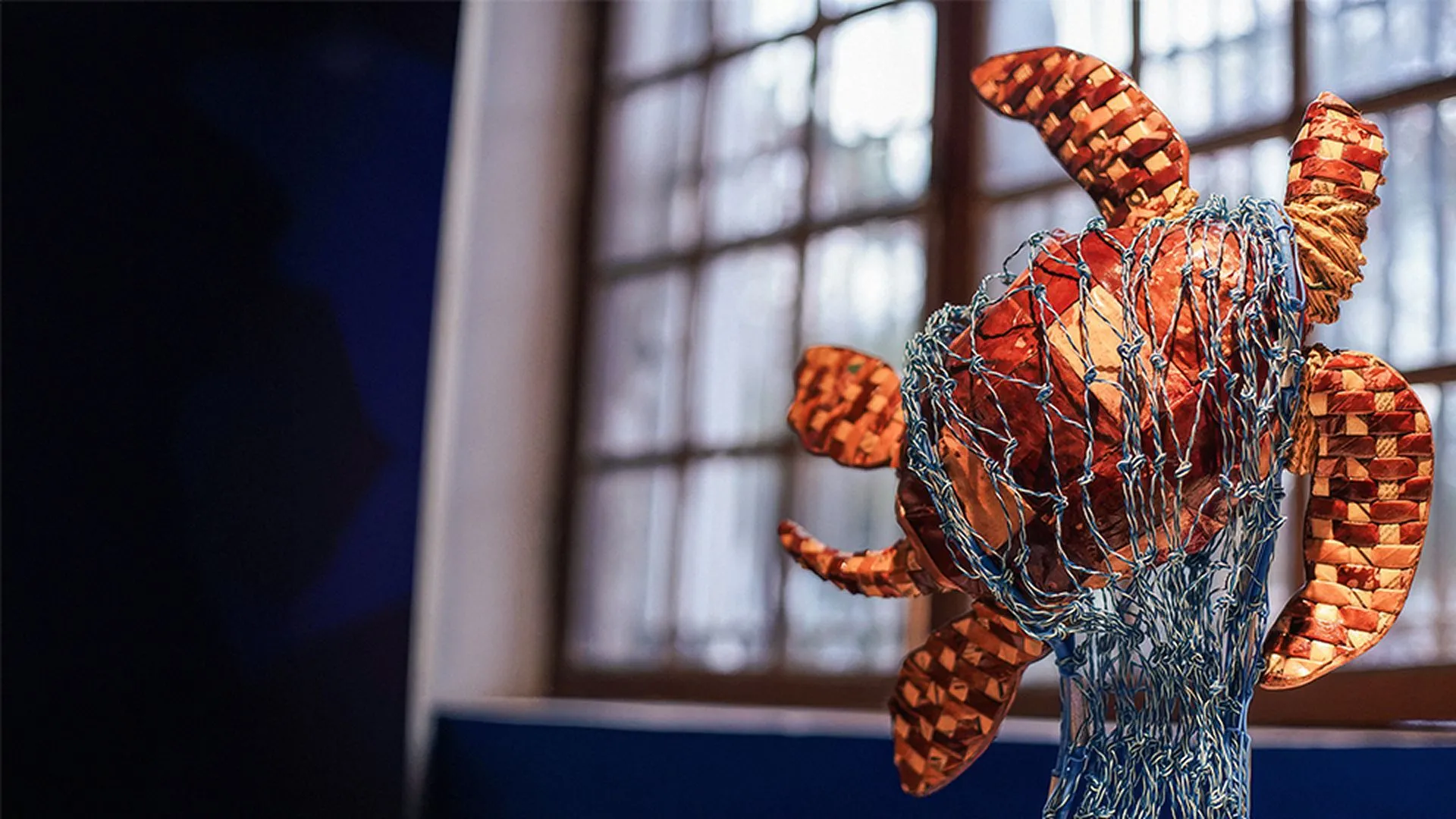 Escultura de tartaruga feita de rede de pesca em contraluz