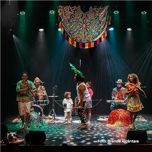 Grupo musical se apresenta sob um painel circular colorido